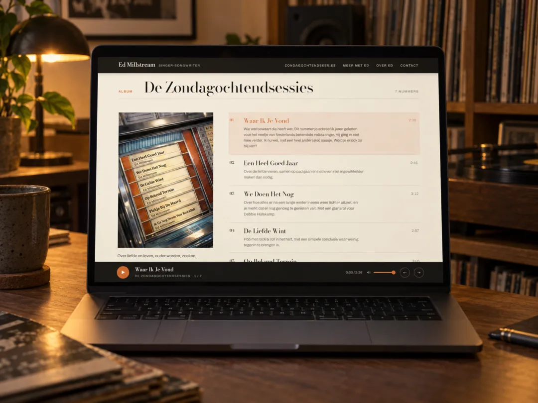 Laptop met de Ed Millstream-website op een houten tafel in een warme muziekkamer met platenkast en lamplicht.